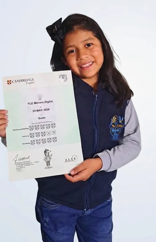 Una alumna del colegio sostiene su certificado de Cambridge English, YLE Movers, en una foto de estudio.