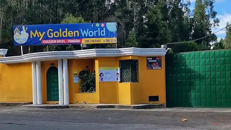 La entrada del colegio desde la avenida: pared amarilla, portón verde y el rótulo de My Golden World sobre la cubierta.